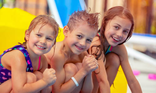 Portrait of a cute happy children having fun in aqua park, joyful siblings with pleasure spending summer holidays on the beach resort